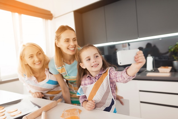 La ragazza in cucina fa selfie con sua madre e sua nonna