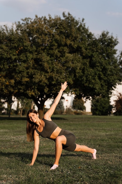 La ragazza in forma fa esercizi di riscaldamento e stretching nel parco verde Stile di vita sportivo