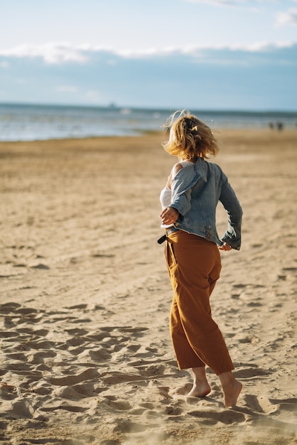 la ragazza in giacca di jeans si gode il sole sulla spiaggia la sera d'estate