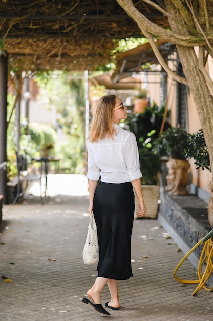 La ragazza in occhiali da sole cammina per le strade europee