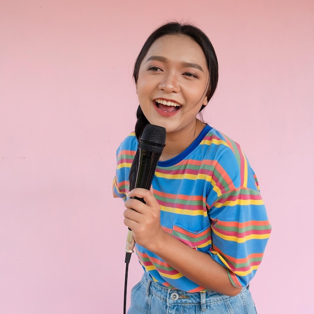 La ragazza in piedi e cantando musica su sfondo rosa