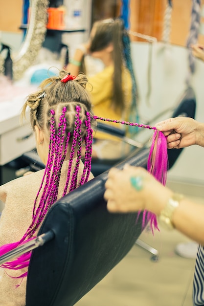 La ragazza in un negozio di barbiere fa le sue afropigtail rosa