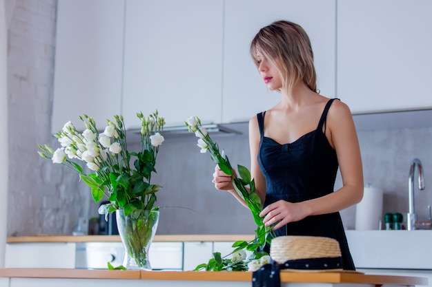 la ragazza in un vestito nero sta tenendo le rose bianche prima di metterle in un vaso