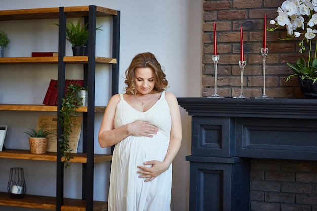 La ragazza incinta con un colpo di pancia e guarda la pancia. Il concetto di maternità felice nella tua grande casa
