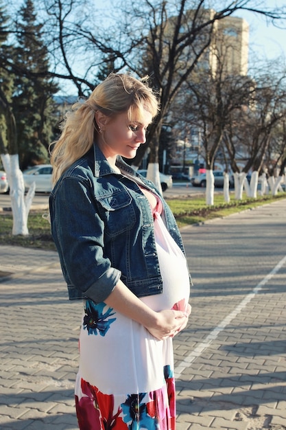 La ragazza incinta sta camminando per il parco cittadino all'inizio della primavera
