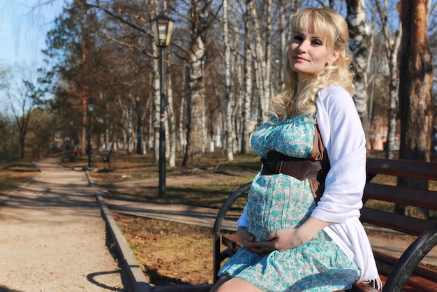 La ragazza incinta sta camminando per il parco cittadino all'inizio della primavera