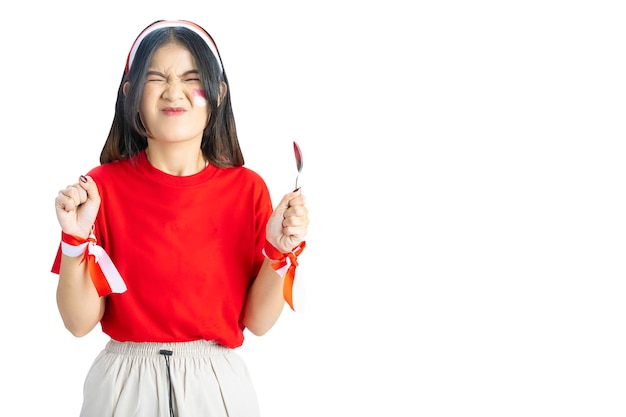 La ragazza indonesiana festeggia il giorno dell'indipendenza indonesiana il 17 agosto con una corsa di biglie usando un cucchiaio isolato su sfondo bianco