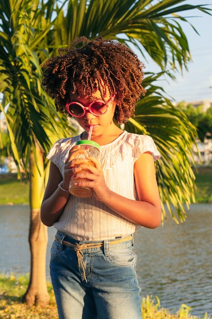 La ragazza ispanica beve il succo dalla bottiglia