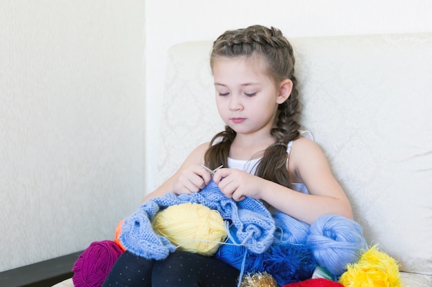 La ragazza lavora a maglia con maglia e filo.