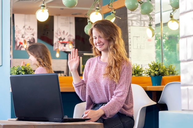 La ragazza lavora su un laptop per il lavoro a distanza in un caffè