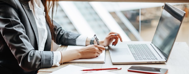 La ragazza lavora su un laptop sul posto di lavoro. Una donna d'affari di successo crea una startup e prende decisioni.