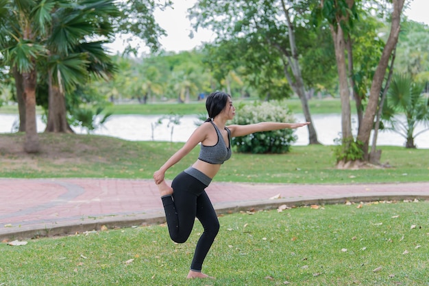 La ragazza magra gioca a yoga sul prato del parco rilassati in nutureAsian Girls ama la salute praticando lo yoga