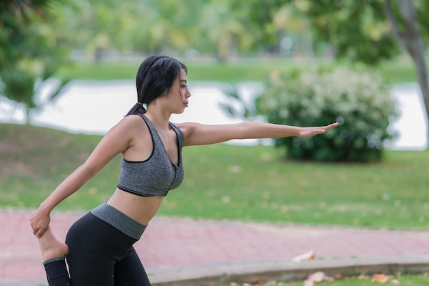 La ragazza magra gioca a yoga sul prato del parco rilassati in nutureAsian Girls ama la salute praticando lo yoga
