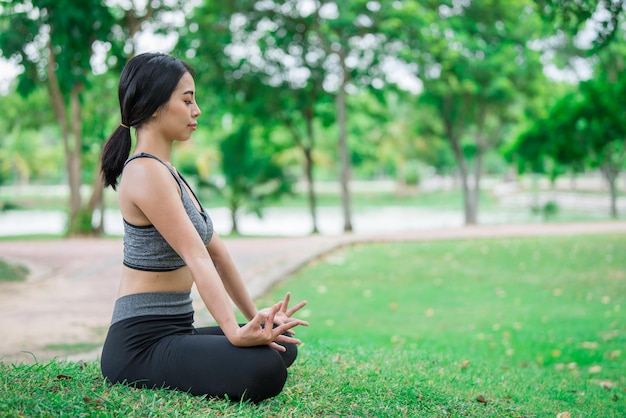 La ragazza magra gioca a yoga sul prato del parco rilassati in nutureAsian Girls ama la salute praticando lo yoga