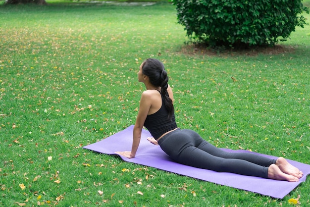 La ragazza magra gioca a yoga sul prato del parco rilassati in nutureAsian Girls ama la salute praticando lo yoga