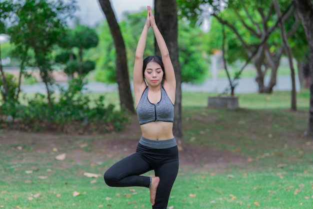 La ragazza magra gioca a yoga sul prato del parco rilassati in nutureAsian Girls ama la salute praticando lo yoga
