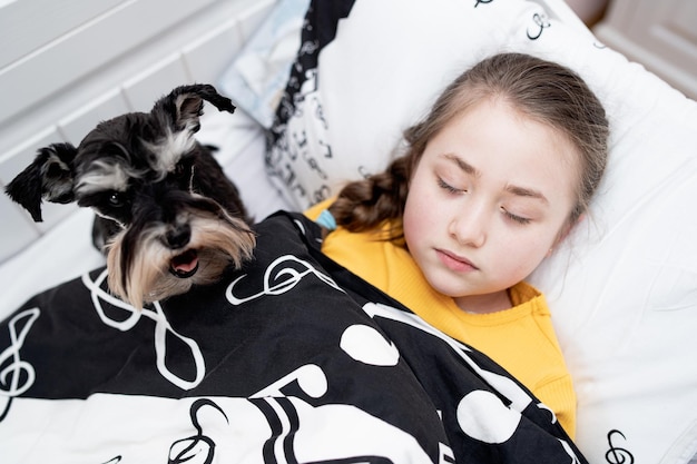 La ragazza malata dorme accanto al suo cucciolo nel letto