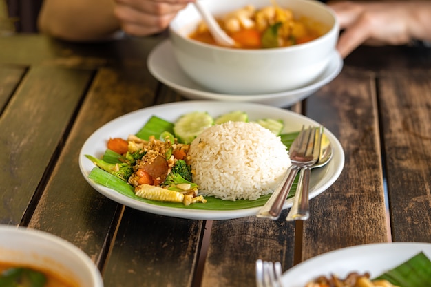 La ragazza mangia cibo tailandese - Tom Yam zuppa e riso tailandese con contorno