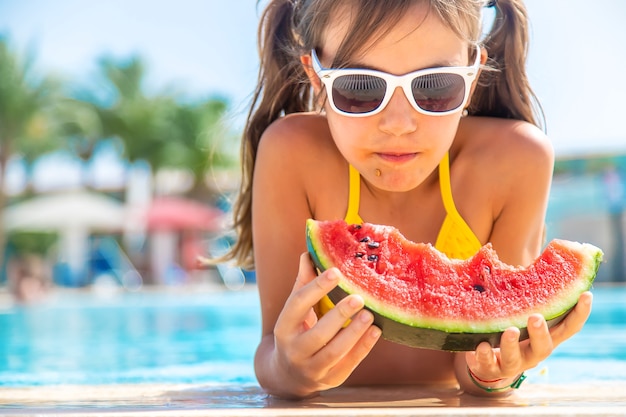 La ragazza mangia l'anguria dentro la piscina