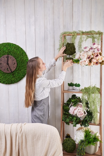 La ragazza mette i fiori sullo scaffale