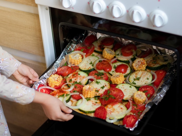 la ragazza mette in forno una teglia con le verdure