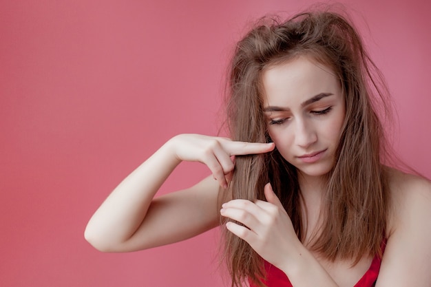 La ragazza mostra le forbici su capelli, concetto di cura dei capelli