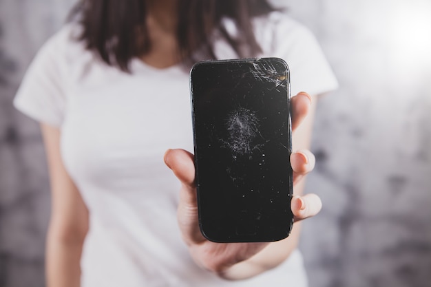 La ragazza mostra un telefono rotto.