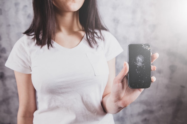 La ragazza mostra un telefono rotto.