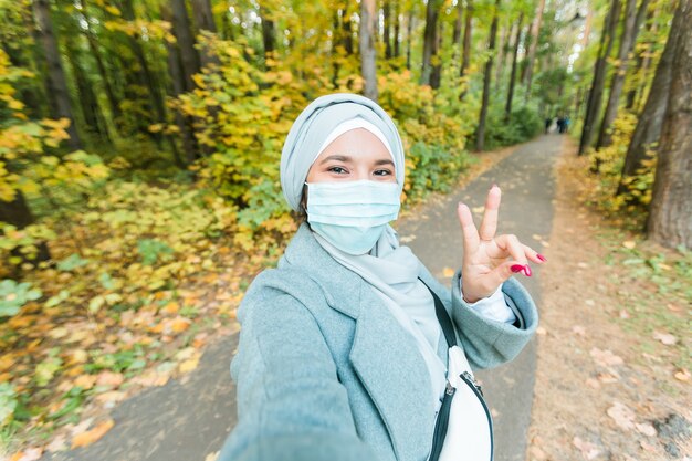 La ragazza musulmana con una maschera medica fa un ritratto selfie di una donna araba islamica nel parco durante a