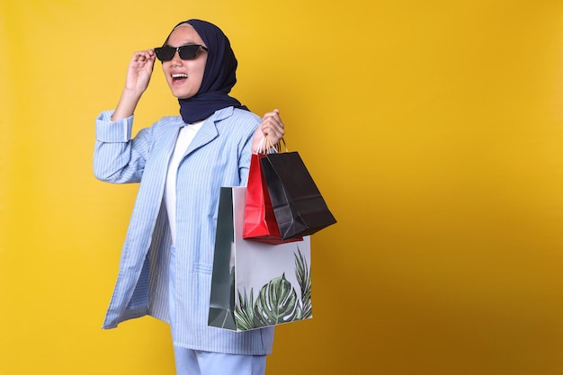 la ragazza musulmana in stile casual si sente felice di fare shopping, portando molte borse della spesa