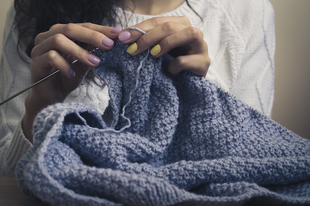 La ragazza nel maglione bianco tricotta il filo blu