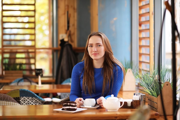 La ragazza nella caffetteria si siede e beve il tè