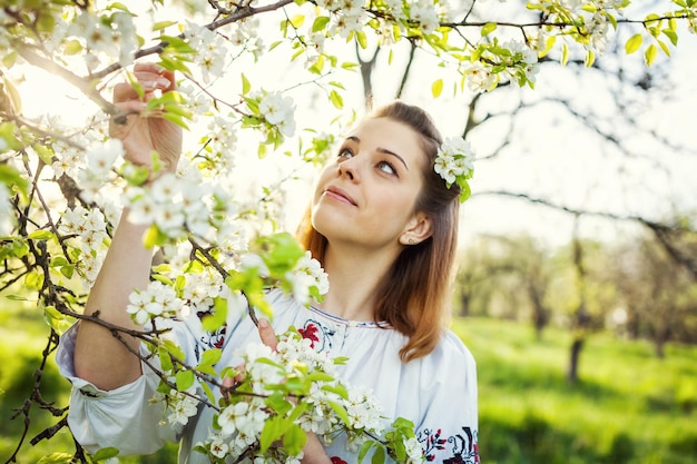 La ragazza nella mattina di primavera in un bellissimo giardino fiorito con in mano un mazzo di fiori