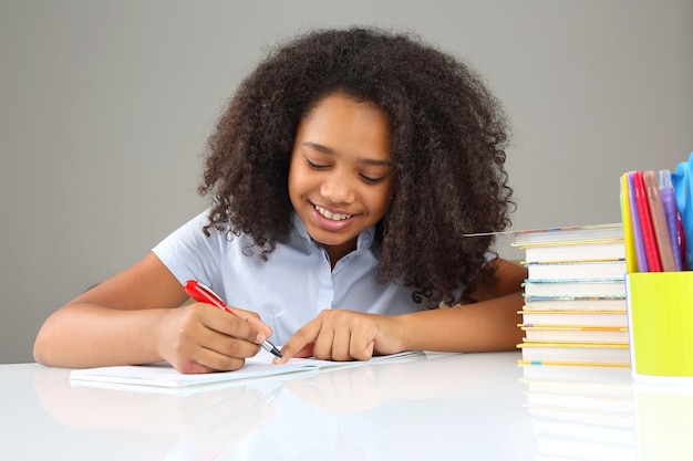 La ragazza nera della scuola scrive in un taccuino, facendo i compiti