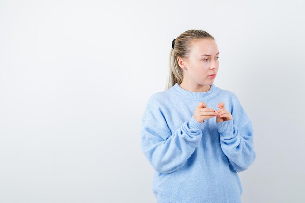 La ragazza piacevole sta pensando e guardando il lato destro su sfondo bianco