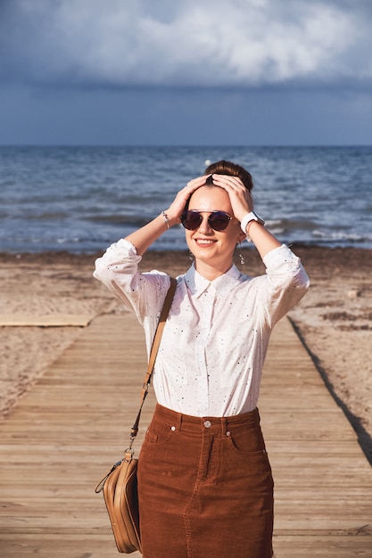 La ragazza posa sulla spiaggia contro il mare.