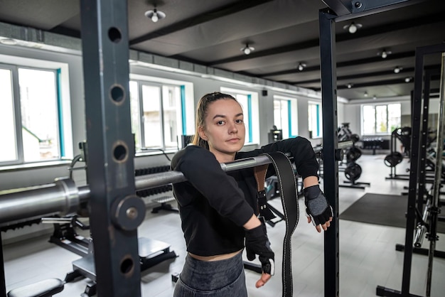 La ragazza pratica esercizi di forza con un nuovo simulatore in una spaziosa palestra per perdere chili in più di luce naturale