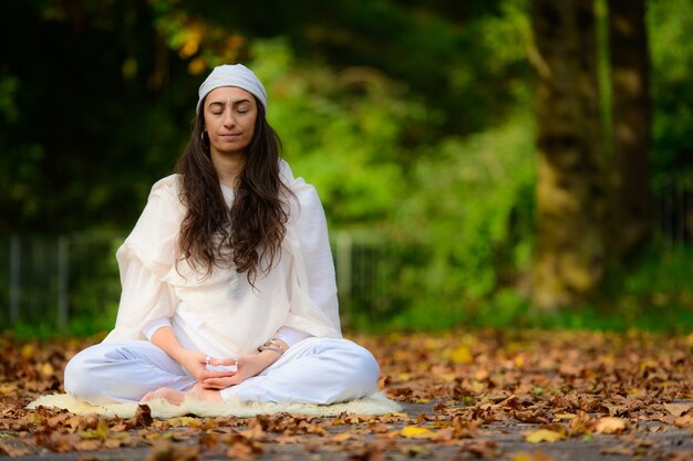 La ragazza pratica lo yoga tra le foglie d'autunno