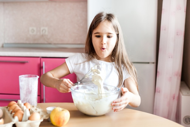 La ragazza prepara la colazione, cuocere al forno, mescolare in una ciotola di farina, latte, uova, frittelle, i bambini aiutano la madre, la famiglia Colazione, cucina