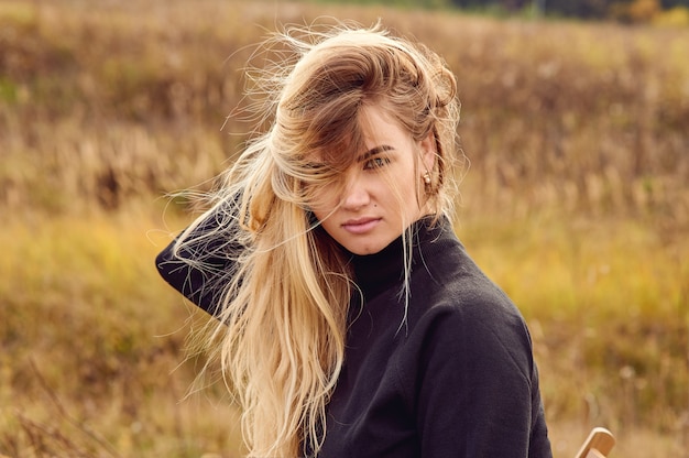 La ragazza raddrizza i capelli con una mano e guarda tra i capelli