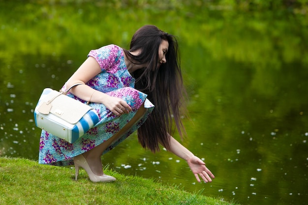 La ragazza raggiunge l'acqua nel parco primaverile