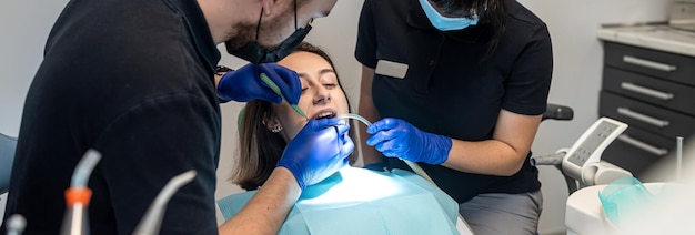 La ragazza ride ad un esame del dentista con un assistente in una clinica odontoiatrica