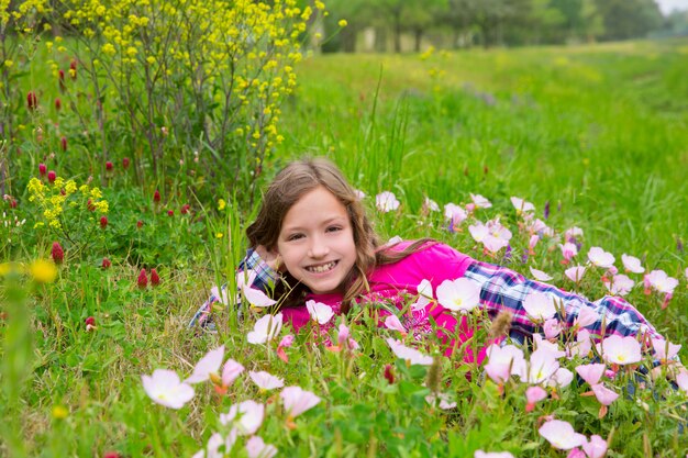 La ragazza rilassata felice del bambino su una molla fiorisce il prato