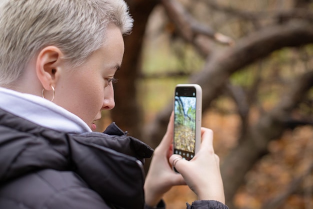 la ragazza scatta una foto del paesaggio autunnale sullo smartphone