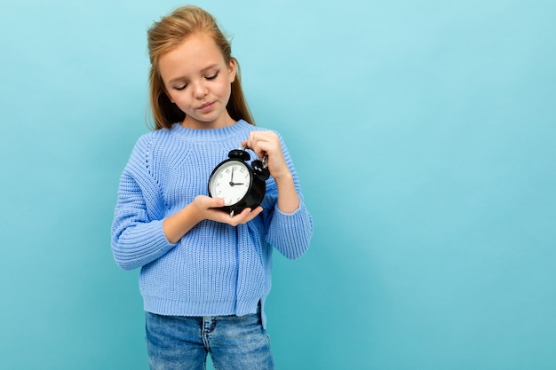 La ragazza scontenta europea guarda il tempo dell'allarme su azzurro