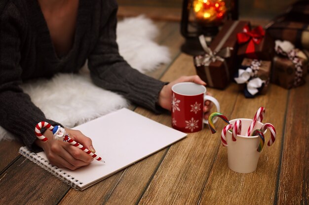 La ragazza scrive a penna su un pezzo di carta auguri di Natale e lettere a Babbo Natale