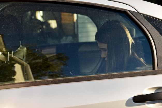 La ragazza seduta in macchina dietro il vetro