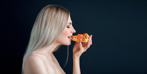 La ragazza sensuale mangia la pizza