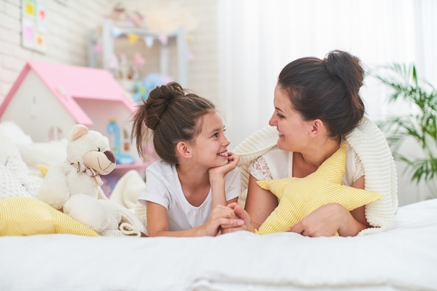 La ragazza si congratula con la madre. La mamma e la figlia sorridono e abbracciano mentre si trovano sul letto.