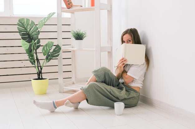 La ragazza si copre il viso con la lettura della letteratura del libro e il concetto di conoscenza